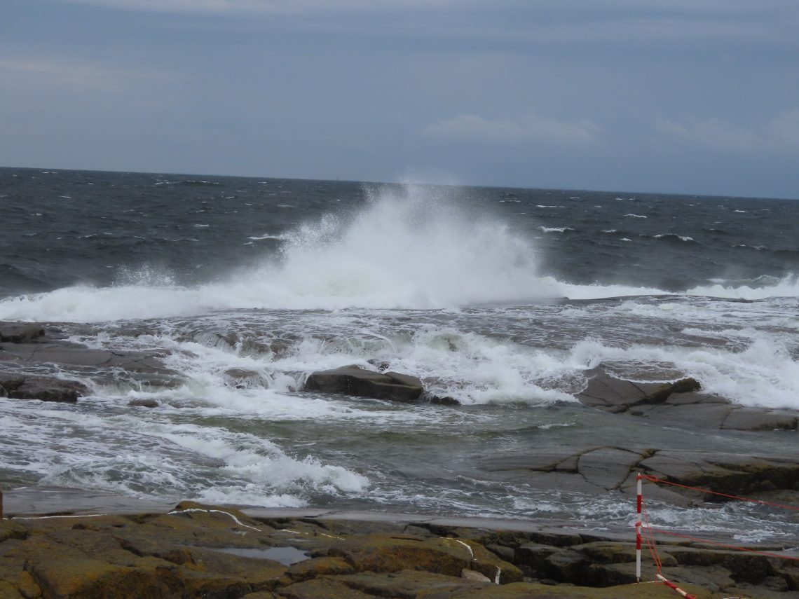 Meren aallot vyöryvät kovassa tuulessa yli luodon