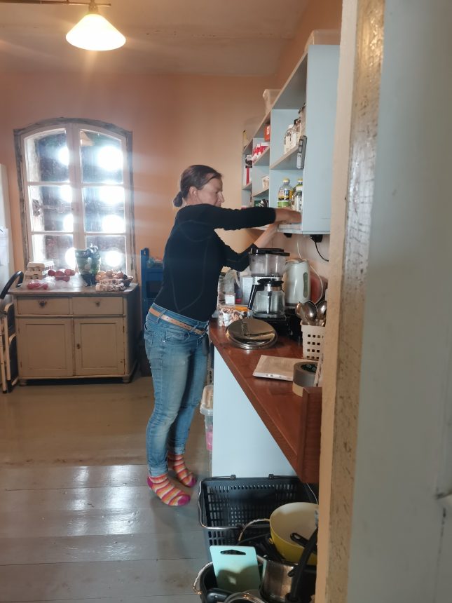 Nainen siivoamassa keittiön hyllyjä