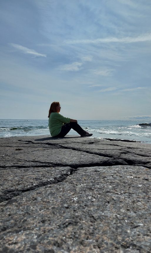 Nainen istuu kalliolla