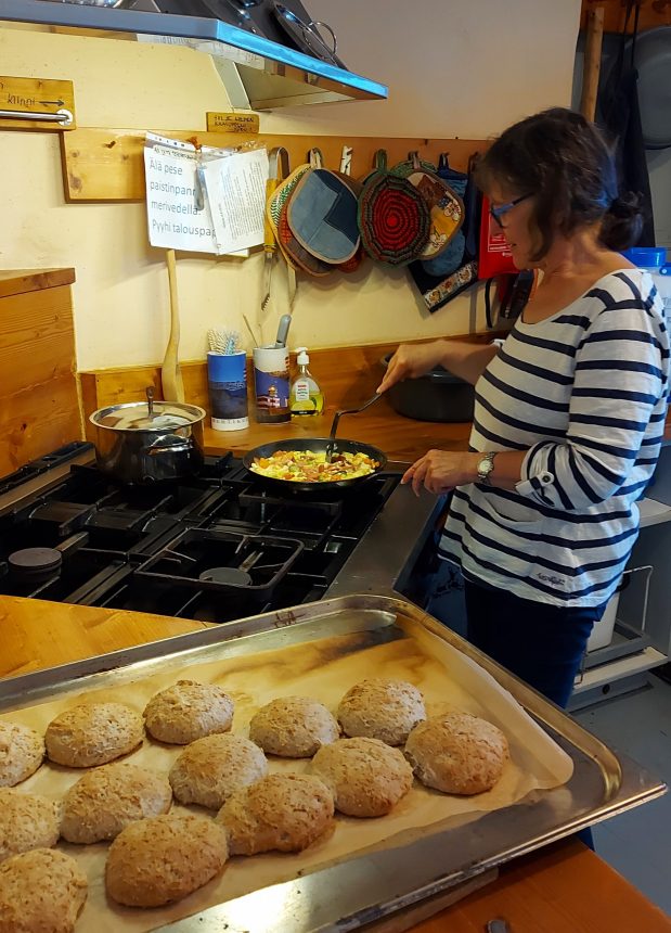 Valmiit sämpylät ja nainen valmistamassa lounasta